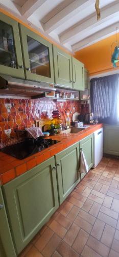 a kitchen with green cabinets and a tile floor at Chambre d'hôtes Le Havre in Saint-Coulomb