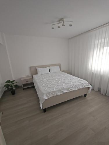a white bedroom with a bed and a window at Apartament Bianco in Brăila
