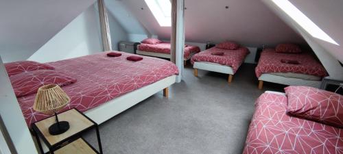a attic room with three beds with red comforters at DUPLEX DE LA MOTTE in Beaumont-sur-Sarthe