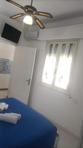 a bedroom with a blue bed and a ceiling fan at Casa Joluì in Torre San Giovanni Ugento