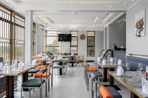 a dining room with tables and chairs and windows at Beal Mall & Hotel in Arua