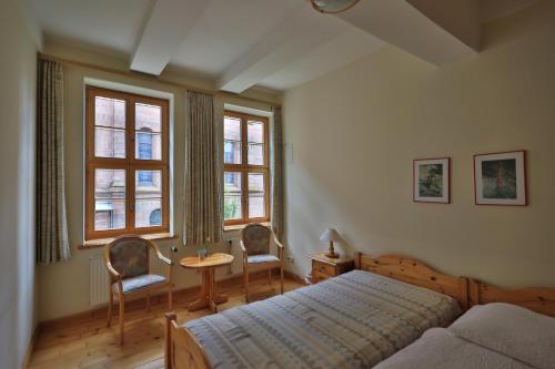 a bedroom with a bed and two chairs and windows at Ursulinenkloster in Duderstadt