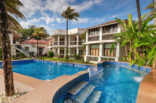 a swimming pool in front of a building at Resort Coqueiral - A Portuguese Heritage Stay by the Sea in Candolim