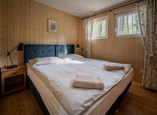 a bedroom with a large bed with two towels on it at Domki Zacisze, Okoniny in Śliwice