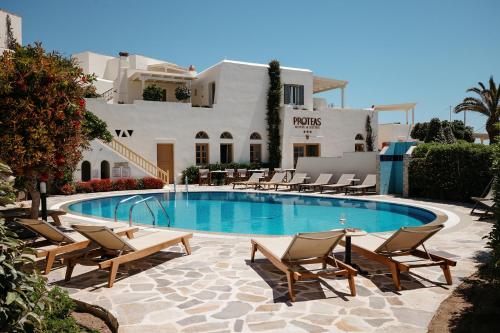 a swimming pool with lounge chairs and a building at Proteas Hotel & Suites in Agios Prokopios