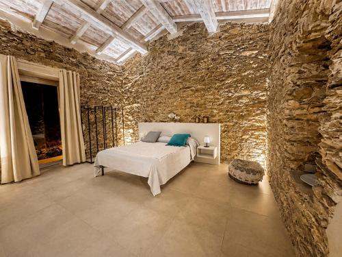 a bedroom with a bed and a stone wall at MP Luxury House in Budoni