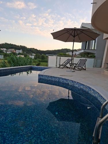 a pool with an umbrella and a table and chairs at Apartments Melisa in Ulcinj