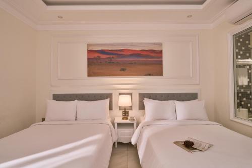 two beds in a white room with a picture on the wall at Nature Hotel - Pham Hong Thai in Da Lat