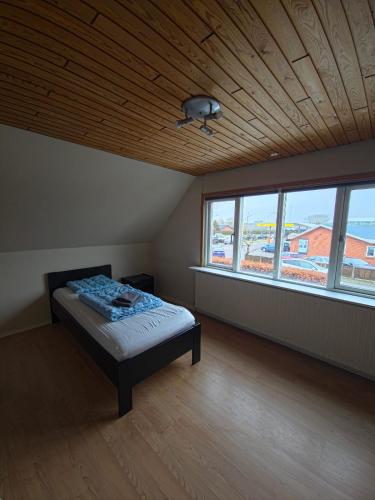 a bedroom with a bed in a room with windows at Glentevej 4 in Ringkøbing