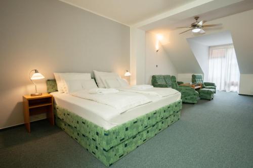a bedroom with a large bed and two chairs at Hotel u Crlíků in Tetčice