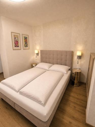 a large white bed in a bedroom with two lamps at Stein 35 with Kitzstainhorn view in Kaprun