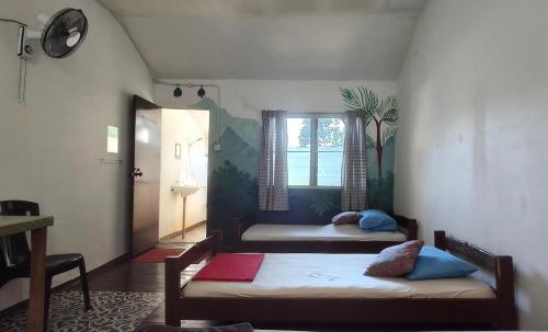 two beds in a small room with a window at Mulu Village in Mulu