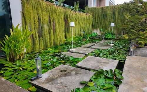 a garden with lilies and plants on a wall at Sunday Sea Two Pool Villa Pattaya in Jomtien Beach