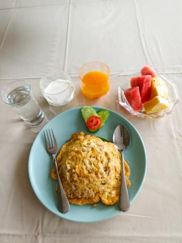 a blue plate with a omelet and fruit on a table at Lanna Oriental Maejo in Chiang Mai