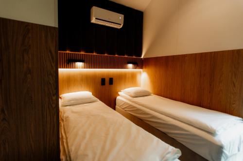 a bedroom with two beds and a air conditioner on the wall at avocado domki in Kuśnie