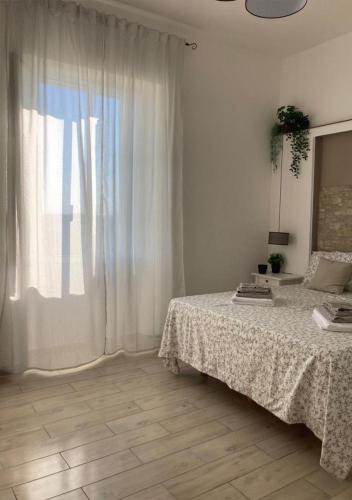 a white bedroom with a bed and a window at Prima Stella Tourist Rooms in Minturno
