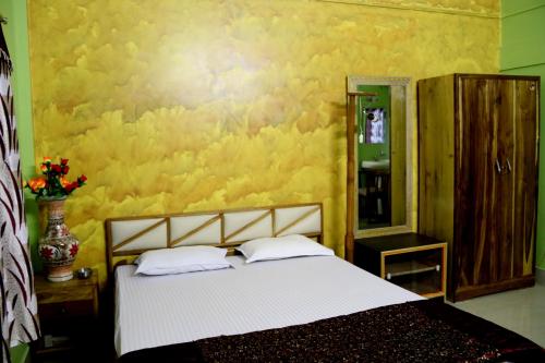 a bedroom with a bed and a yellow wall at Hotel Alohi Ghar in Jorhat
