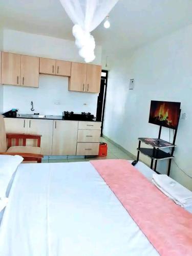 a bedroom with a large white bed and a kitchen at Romantic Cage in Rungiri