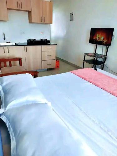 a bedroom with two white beds and a kitchen at Romantic Cage in Rungiri