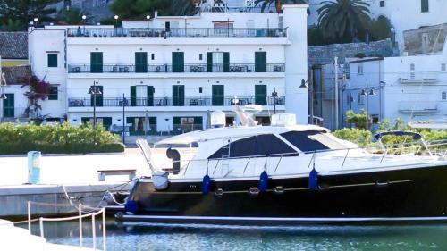 a boat docked in the water in front of a building at Hotel Rodi Beach FRONTE SPIAGGIA in Rodi Garganico