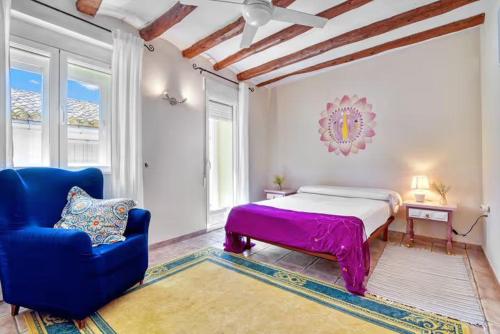 a bedroom with a bed and a blue chair at Dhara Wellness Villa in Benirrama