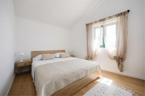 a white bedroom with a bed and a window at Seafront Villa in Kornati Private Terrace and Direct Beach Access in Kornati