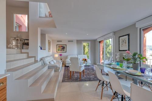 a dining room and living room with stairs and a table at Villa sur les hauteurs de Nice, proche centre in Nice