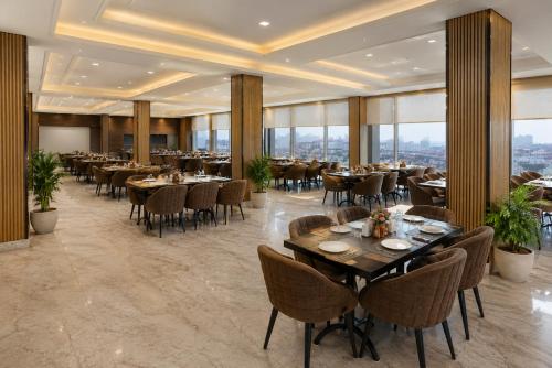 a dining room with tables and chairs and windows at Hotel Park Green Suites Delhi Airport in New Delhi