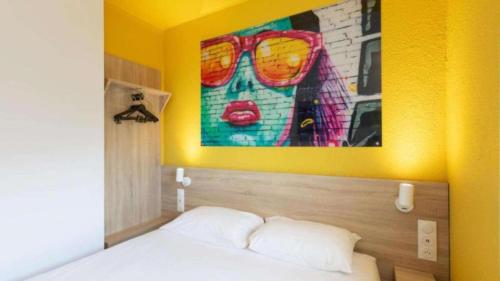 a room with a bed with a painting on the wall at Kyriad ECO - Dijon Sud Chenove in Chenôve