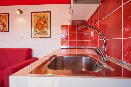 a kitchen sink with a red tiled wall at Poggio Diavolino - Suvereto in Suvereto