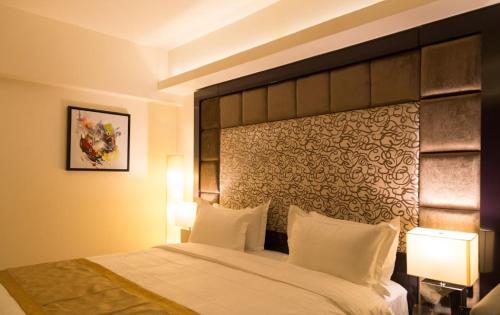 a bedroom with a large bed with a large headboard at Hotel Oxina Lygon in Tiruchchirāppalli