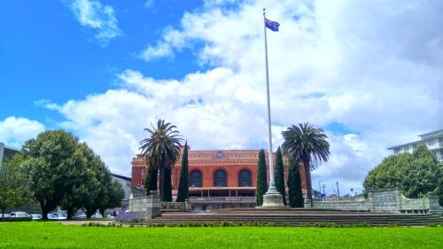 a flag pole in front of a building with palm trees at Grand Central Serviced Apartments in Auckland