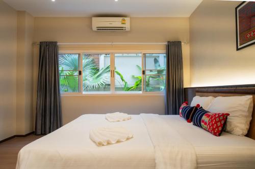 a bedroom with a large white bed with a window at The Opium Chiang Mai in Chiang Mai