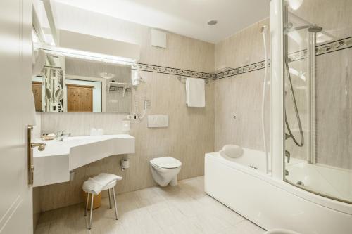 a bathroom with a sink and a tub and a toilet at NaturResidence Dolomitenhof in Siusi