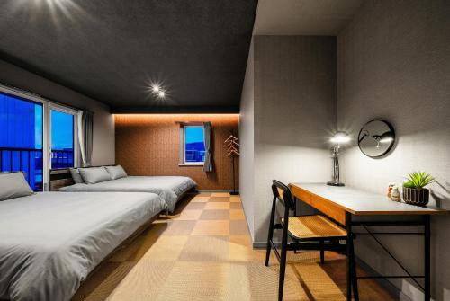 a room with two beds and a desk and a table at The Lavenridge in Nakafurano