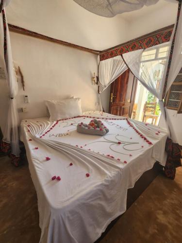 a bedroom with a white bed with flowers on it at Wow Beach House in Jambiani