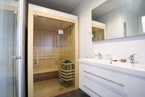 a bathroom with a shower and a sink and a mirror at Cube la Mer 4 in Olburgen