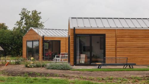 a wooden tiny house with a bench in the yard at Cube la Mer 4 in Olburgen
