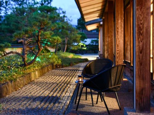 two chairs sitting on the porch of a house at Senkeien Tsukioka Hotel in Kaminoyama