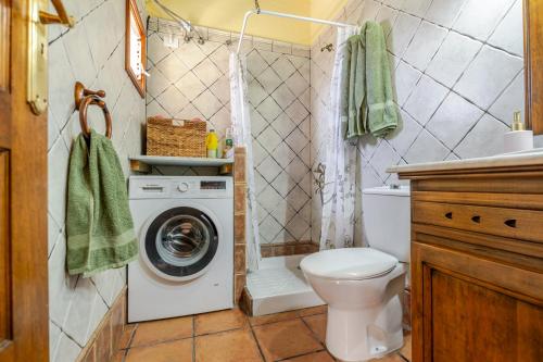 a bathroom with a toilet and a washing machine at Tasarte by Villas Rivero in Tasarte
