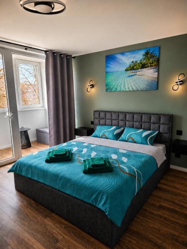 a bedroom with a large bed with a blue comforter at Baltijos Apartamentai, Self check-in, free parking in Klaipėda