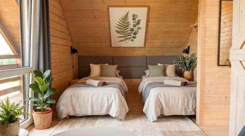 three beds in a room with wooden walls at Jotwingia - Domki z Widokiem in Stare Juchy