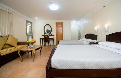 a bedroom with two beds and a couch and a mirror at El Centro Beach Resort Boracay in Boracay