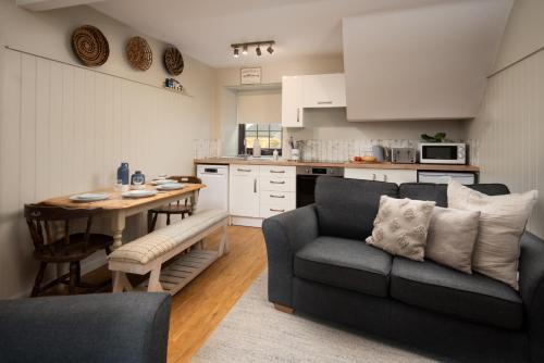 a living room with a couch and a table in a kitchen at Town Farm Cottages Beadnell by Coast & Country Stays in Beadnell
