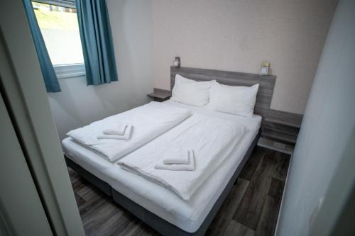 a bedroom with a bed with white sheets and pillows at Chaletpark Petzen in Feistritz ob Bleiburg