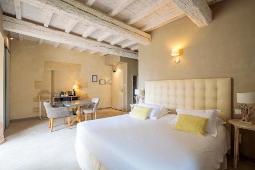 a bedroom with a large white bed and a desk at Boutique Hôtel La Villa Montesquieu & sa piscine in Laudun