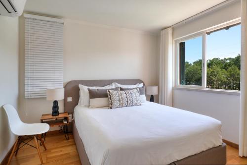 a white bedroom with a bed and a window at bwelcome aroeira beach & golf in Charneca