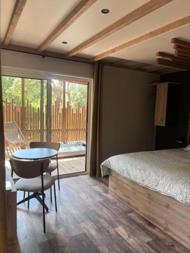 a bedroom with a bed and a table and a window at Camping Familial Buffalo Hacienda in La Seyne-sur-Mer