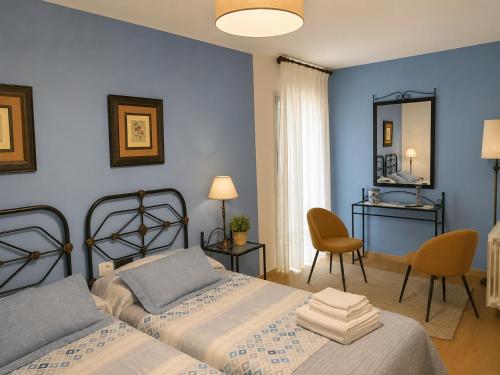 a blue bedroom with two beds and a mirror at Casa Ravel in Silleda