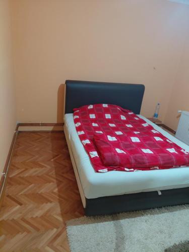 a bed with a red and white blanket on it at Marinel in Vršac